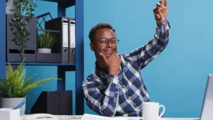 Smiling young entrepreneur holding house keys while sitting at office desk