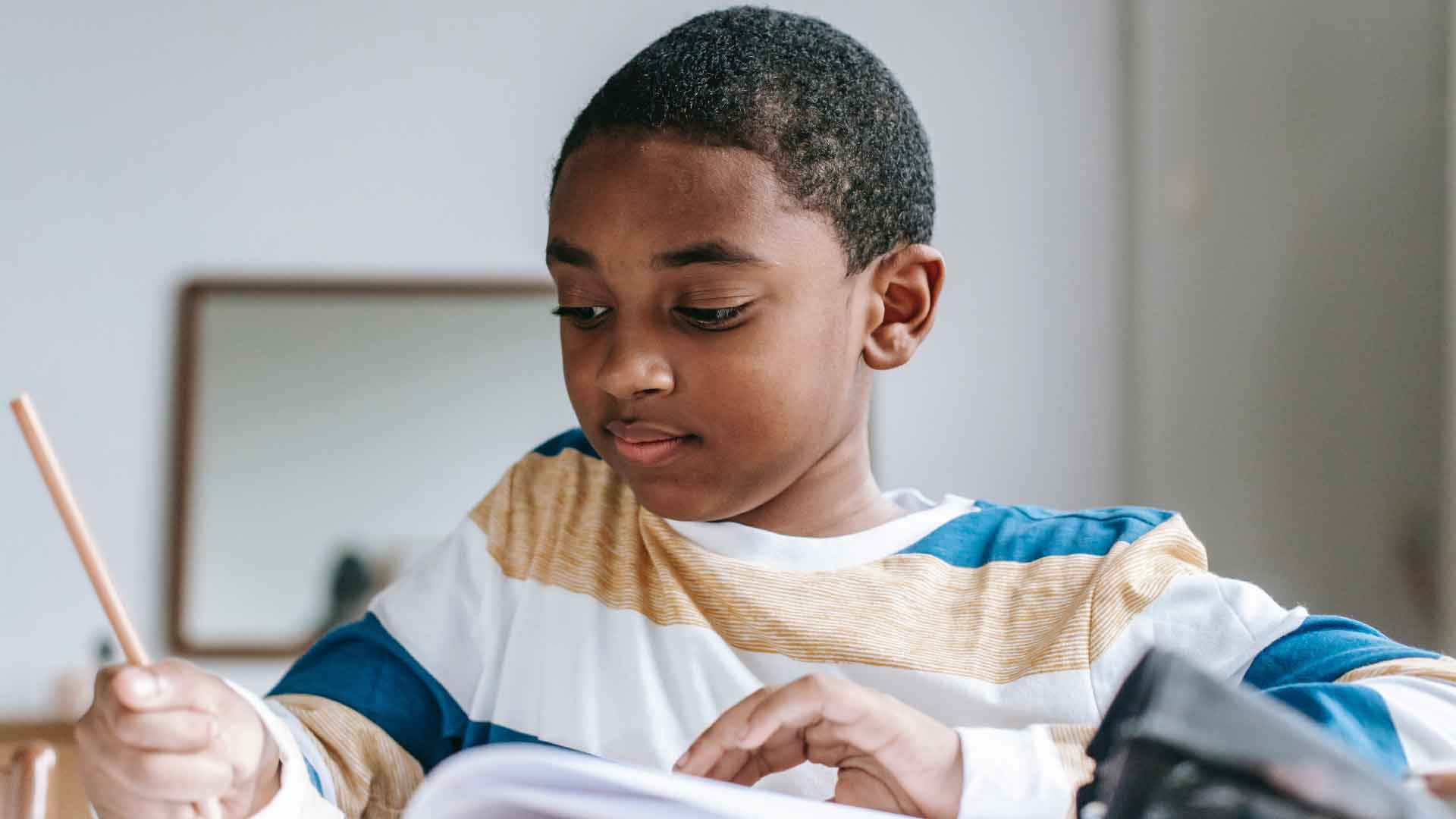 Student boy in a writing in a book