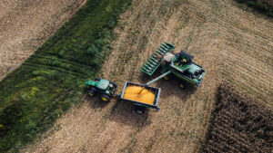 Aerial view of combine harvester unloading corn into a tractor trailer on a farm field