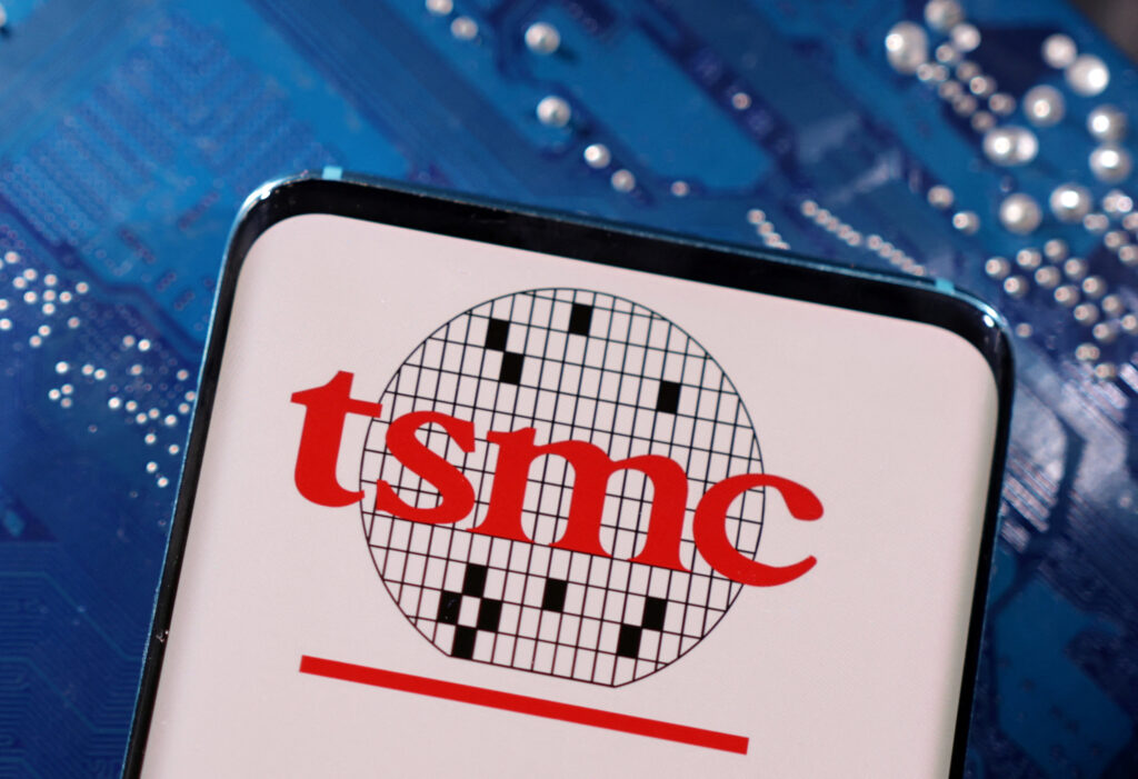 A smartphone with a displayed tsmc taiwan semiconductor manufacturing company logo is placed on a computer motherboard in this illustration taken