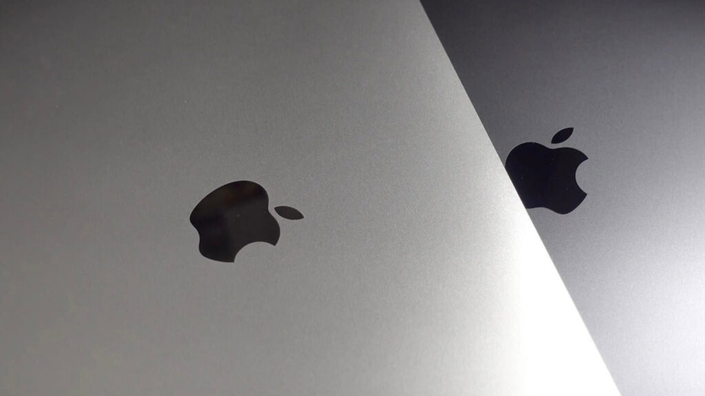Close up of apple logos on silver and space gray apple devices highlighting the brands iconic design