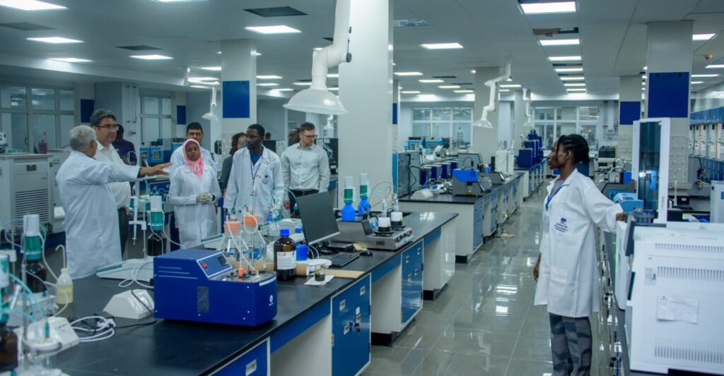 Staff members in lab coats engaged in a discussion inside a modern laboratory at the dangote refinery surrounded by scientific equipment and workstations