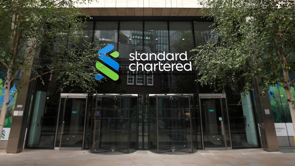 Entrance of standard chartered bank headquarters with the companys logo on the building facade