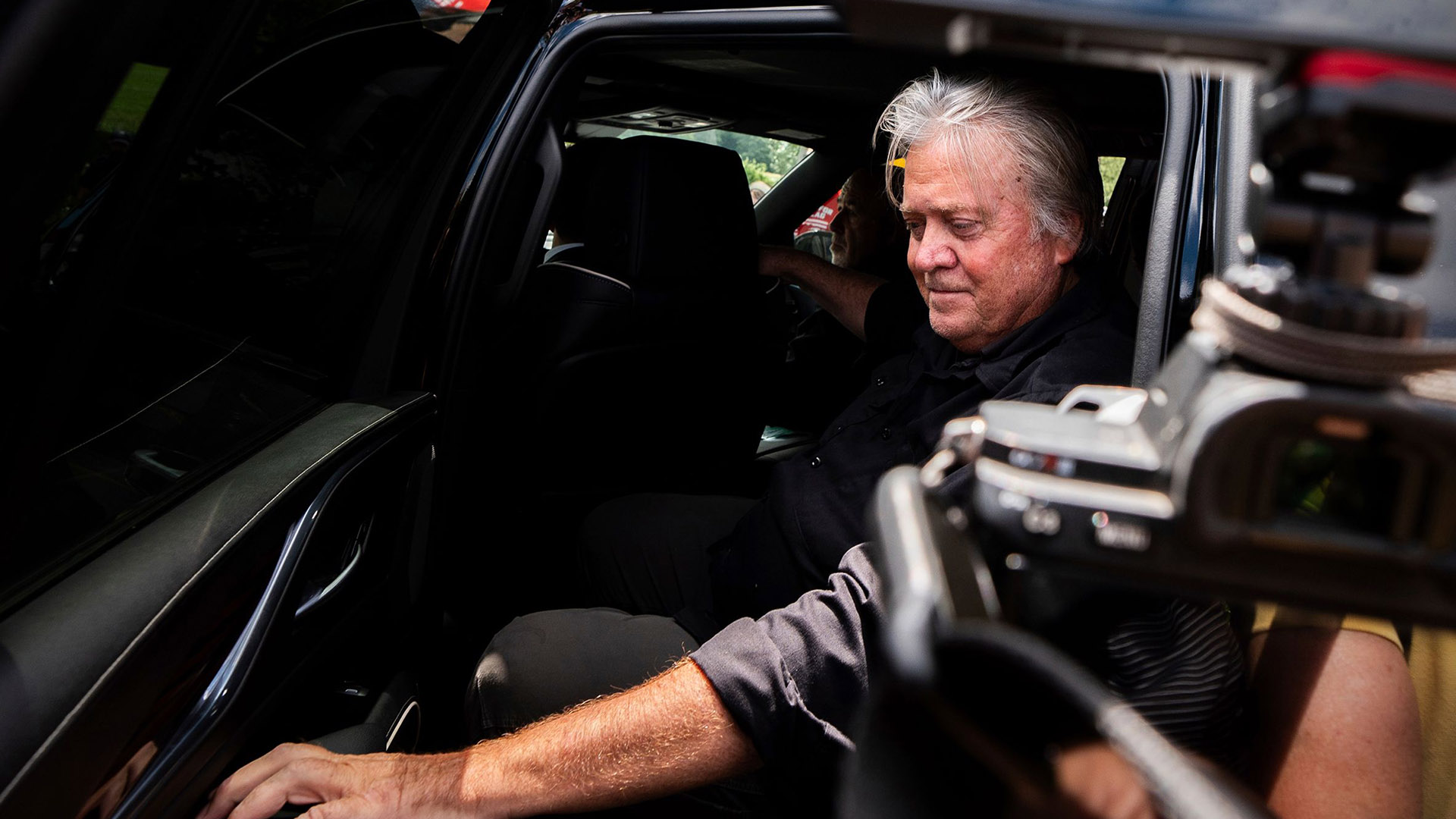 A Notable Exit | Brimco Close up of a man seated inside a vehicle with media equipment partially visible in the frame