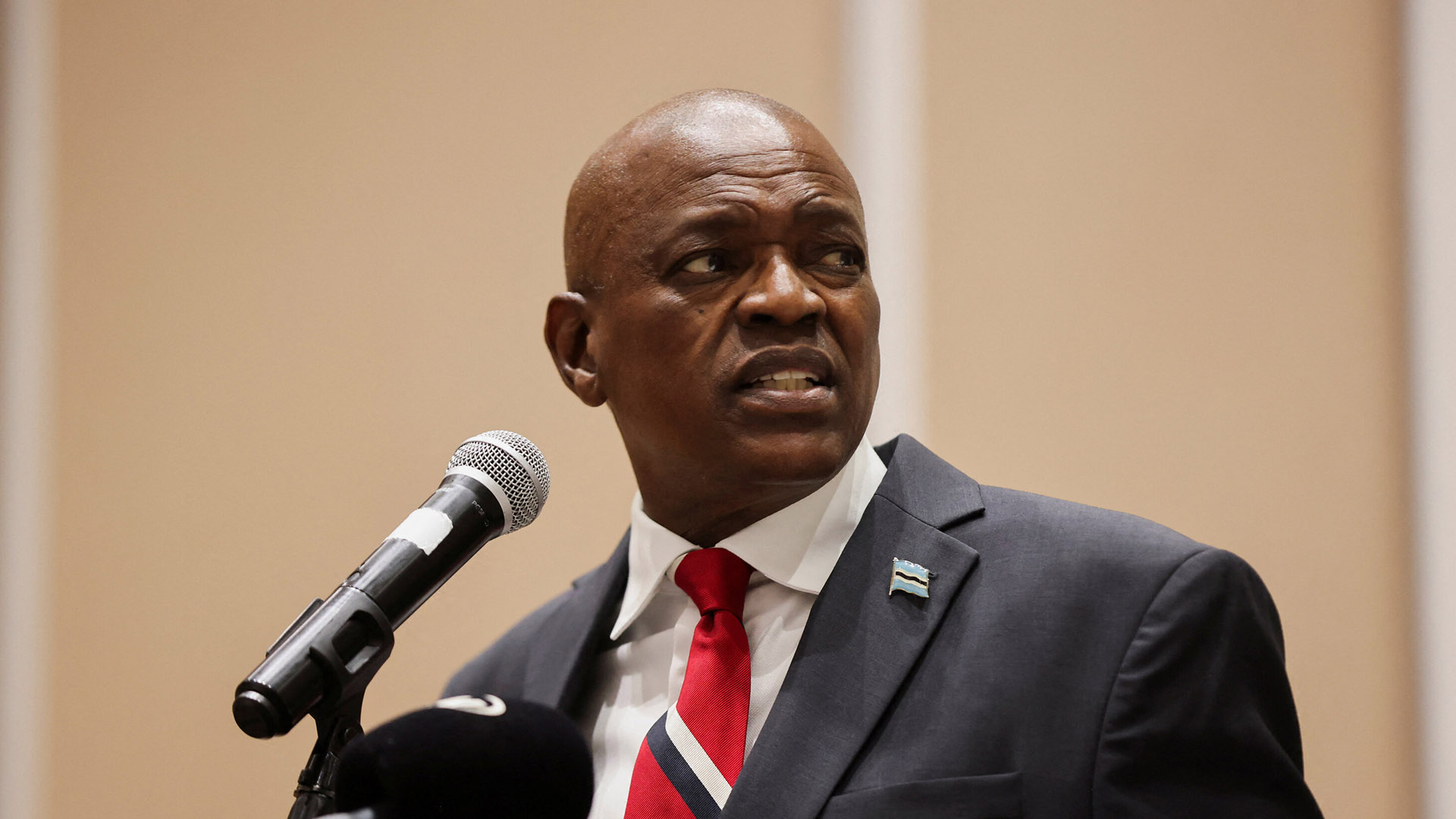 BDP Concedes Power After 58 Years | Brimco President mokgweetsi masisi wearing a suit and red striped tie speaks into a microphone looking to the side with a serious expression during his concession speech