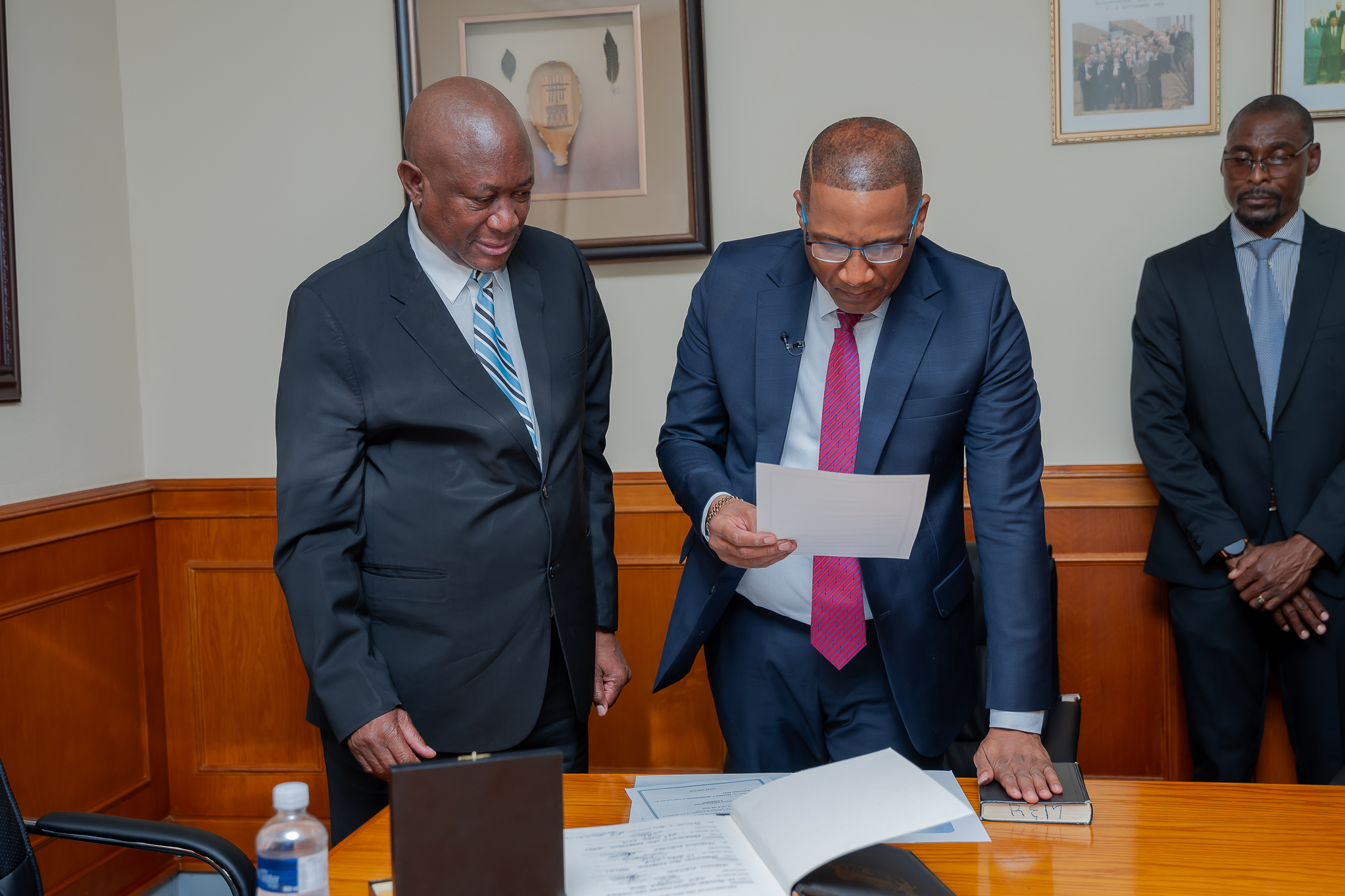 President Duma Bokos Swearing-In Ceremony | Brimco President duma boko being sworn in by chief justice hon Justice terence t Rannowane on november 1 2024 Both are dressed in formal suits standing over official documents in a ceremonial setting