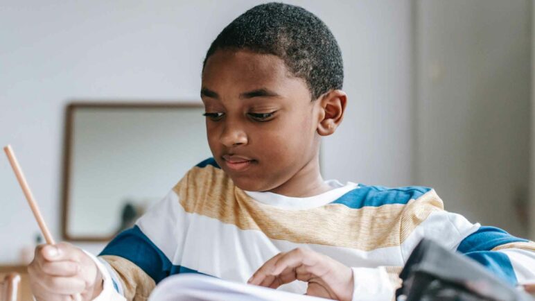 Student boy in a writing in a book