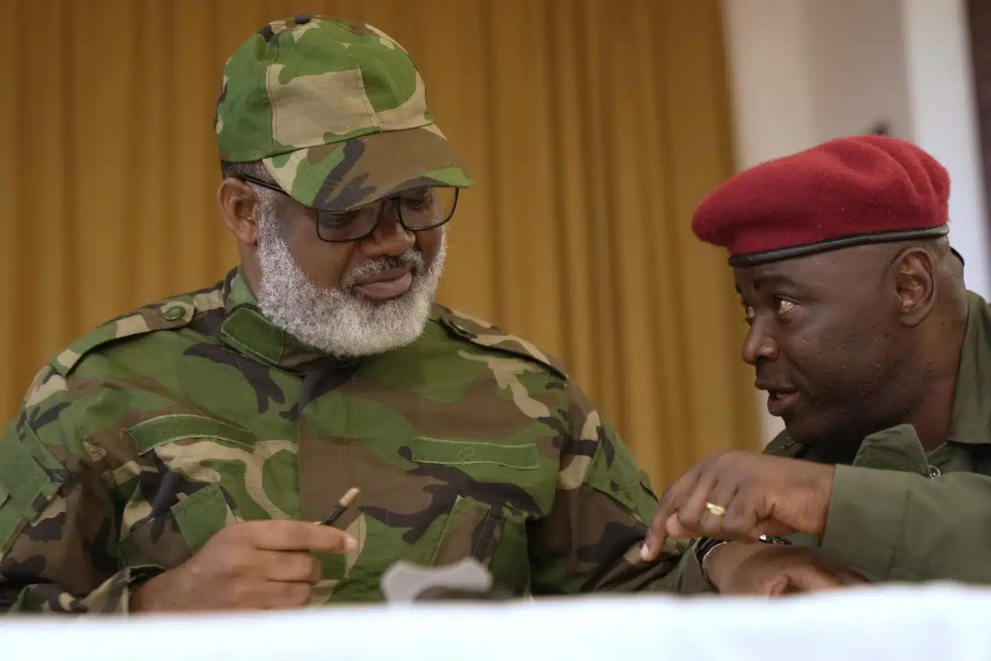 Corneille Nangaa Solidifies Alliance with Rebel Leadership in DRC | Brimco Corneille nangaa wearing camouflage military attire and glasses consults with a red beret military official at a meeting