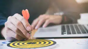 Close up of a hand placing a dart at the center of a target symbolizing precision in business strategy and goal setting