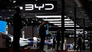 People viewing byd electric vehicles at an auto expo under a brightly lit byd logo