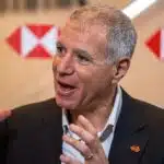 HSBC CEO Georges Elhedery speaking at a finance summit with HSBC logo in background.