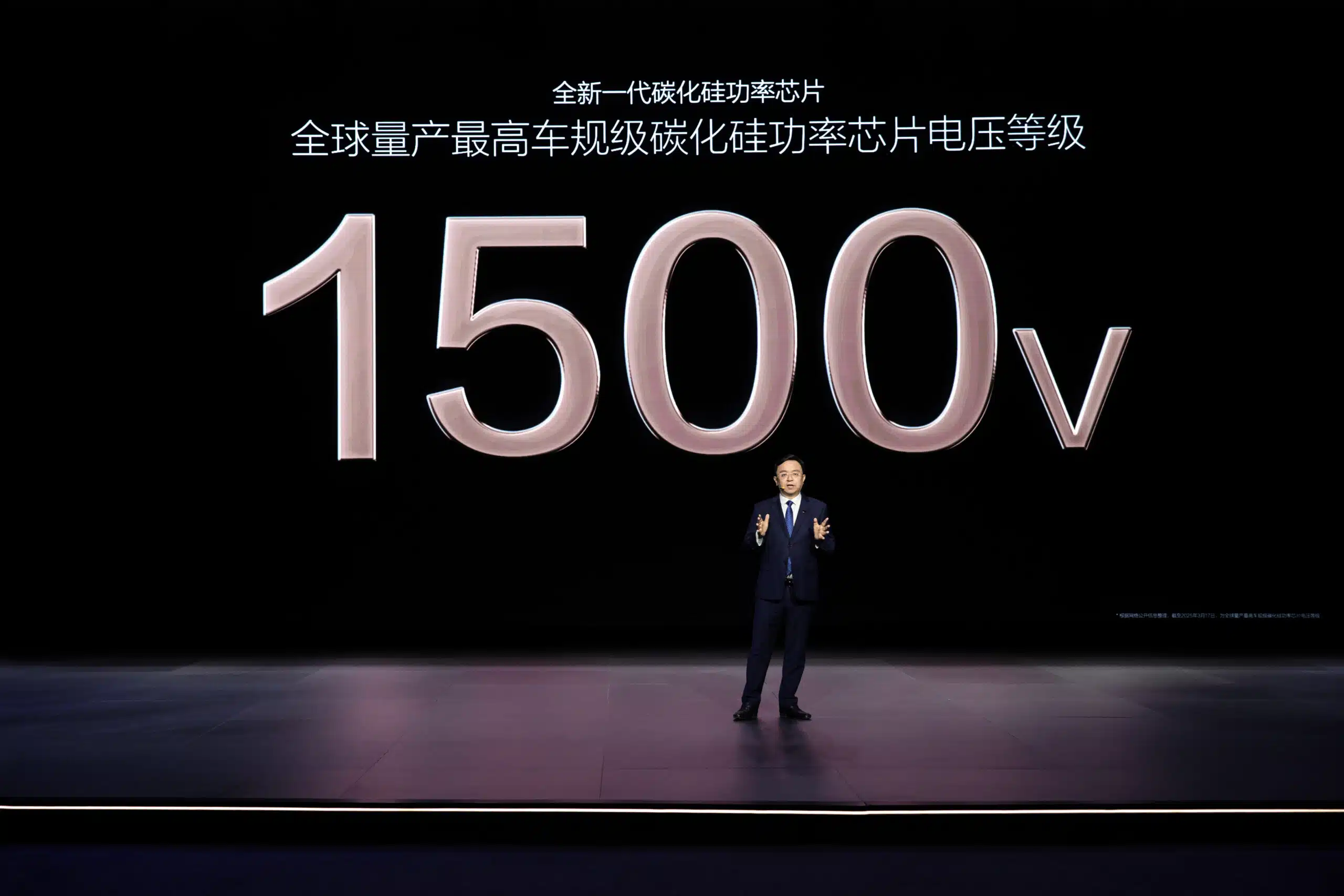 P9-Nxt Generation Automotive-Grade Sic Power Chips | Brimco Byd executive presents 1500v silicon carbide chip on stage with large voltage graphic behind