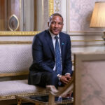 President duma boko seated on a vintage sofa in a diplomatic lounge with a lamp beside him