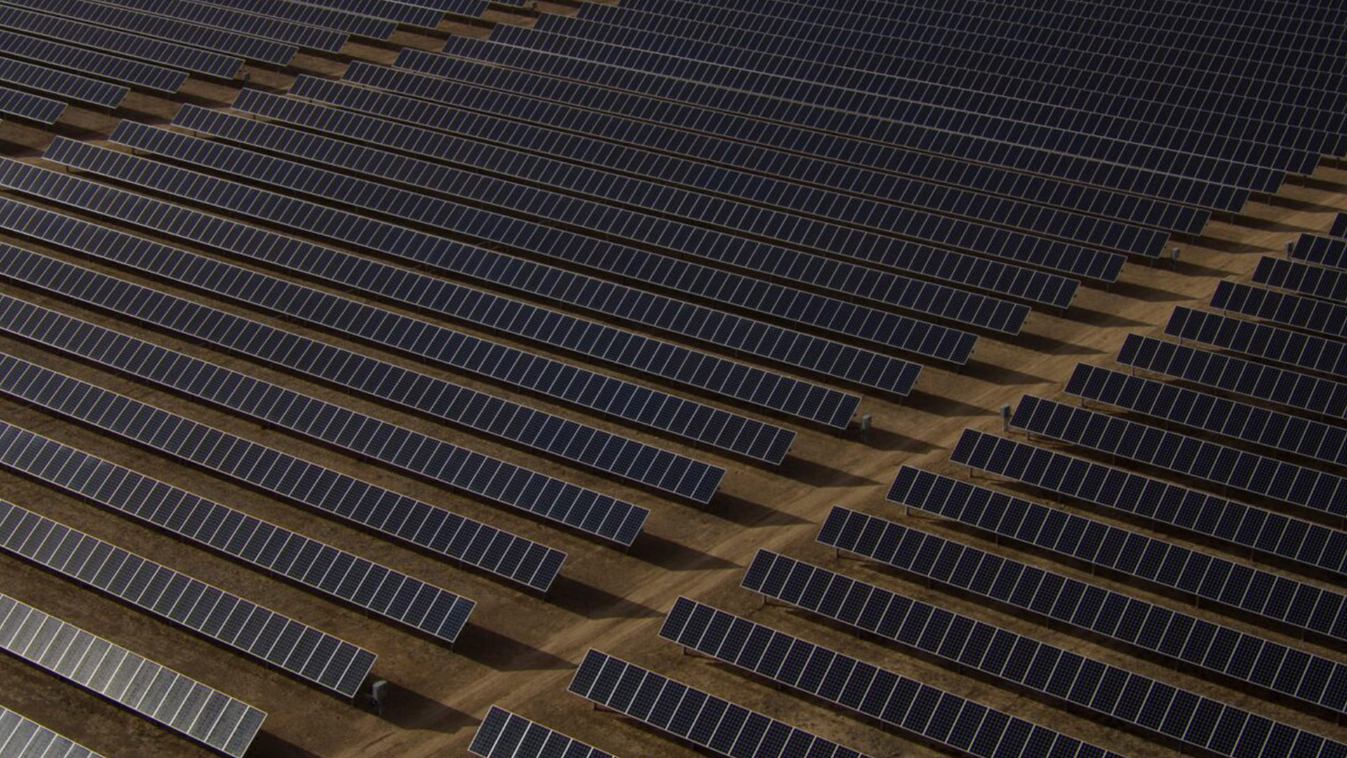 Aerial View of a Solar Farm Powering the Future | Brimco Aerial view of large scale solar panel farm arranged in symmetrical rows on dry land