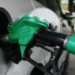 Close up of a green petrol nozzle fueling a silver car at a nigerian filling station
