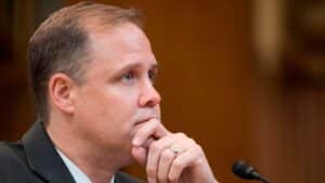 Jim bridenstine in a suit with hand on chin listening during a congressional hearing