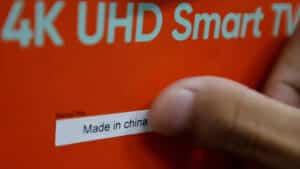 Hand applying a made in china sticker on an orange 4k uhd smart tv box at a chinese factory