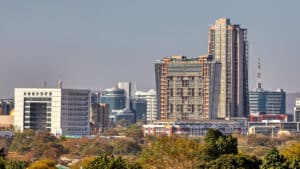 City skyline of gaborone botswana with tall buildings trees in the foreground and hills in the distance