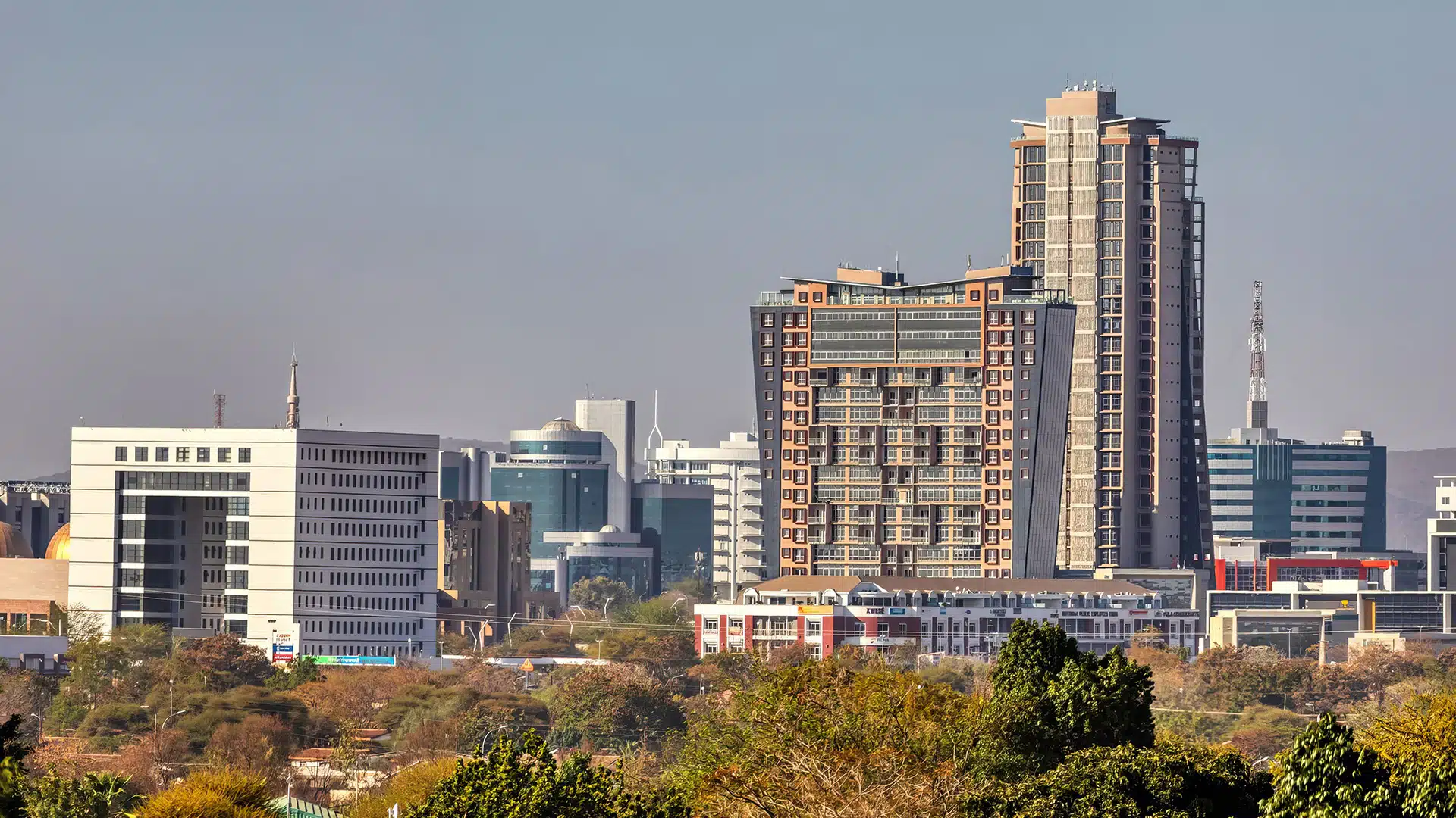 Skyline of Gaborone CBD Botswanas Growing Capital of Opportunity | Brimco City skyline of gaborone botswana with tall buildings trees in the foreground and hills in the distance