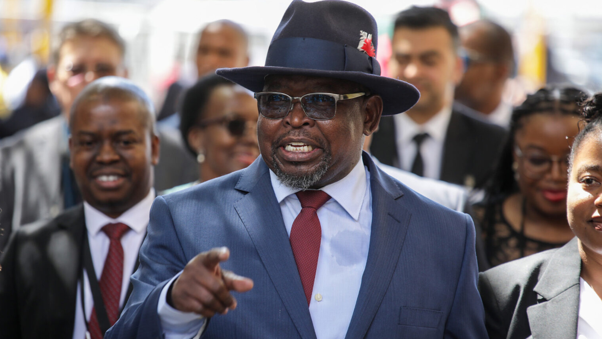 South African Finance Minister Enoch Godongwana | Brimco Enoch godongwana south african finance minister smiling and pointing while wearing a suit and hat at a public event
