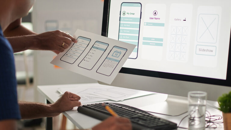 Ux designers reviewing mobile interface prototypes and website feature layouts on a computer screen