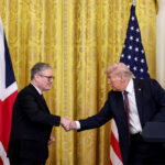 President Donald J. Trump and UK Labour Leader Keir Starmer shaking hands during a joint press conference with American and British flags in the background.