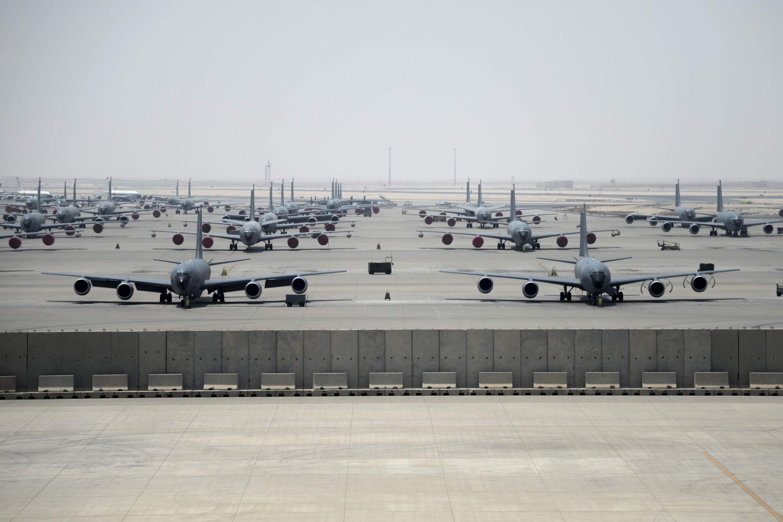 Multiple kc 135 stratotanker aircraft parked at al udeid air base in qatar lined up on the tarmac under a hazy sky