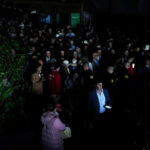 Large crowd standing in a dark venue using phone flashlights during a power outage