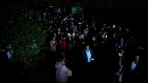 Large crowd standing in a dark venue using phone flashlights during a power outage