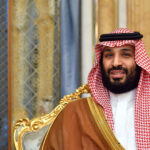 Crown Prince Mohammed bin Salman in traditional Saudi attire, seated on a gilded chair with the Saudi flag in the background.