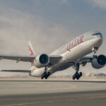 Qatar airways boeing 777 taking off from a runway with landing gear still extended