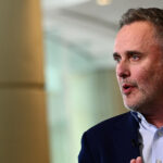 Robin Vince, CEO of BNY Mellon, in a navy blue suit speaking with hands clasped during a formal discussion.