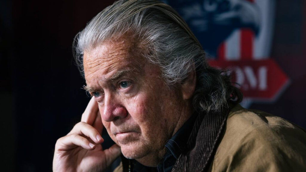 Steve bannon sitting in thought with an american eagle emblem in the background