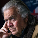 Steve bannon sitting in thought with an american eagle emblem in the background