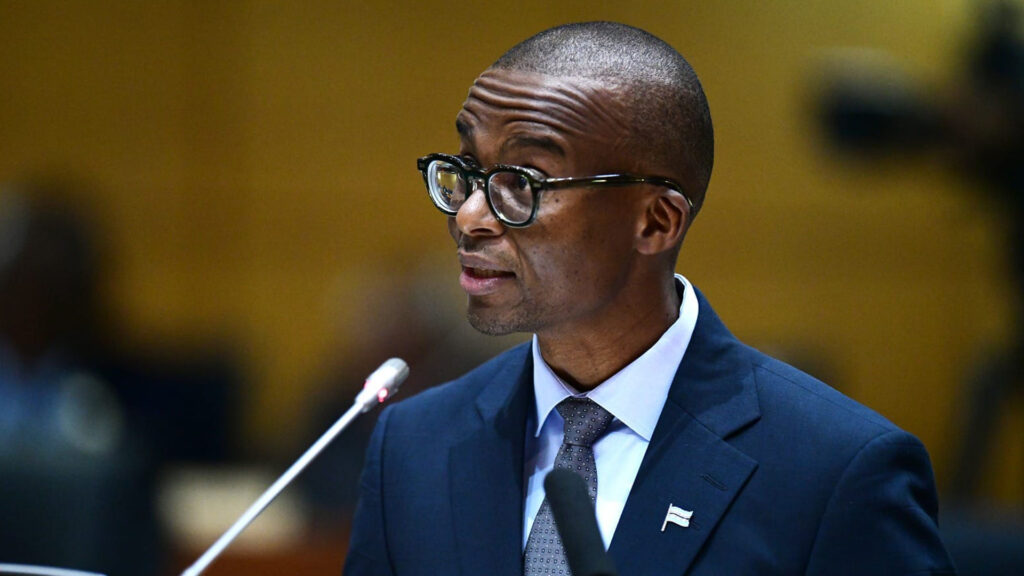 Botswana vice president ndaba gaolathe speaking at the national assembly podium in a navy suit and glasses