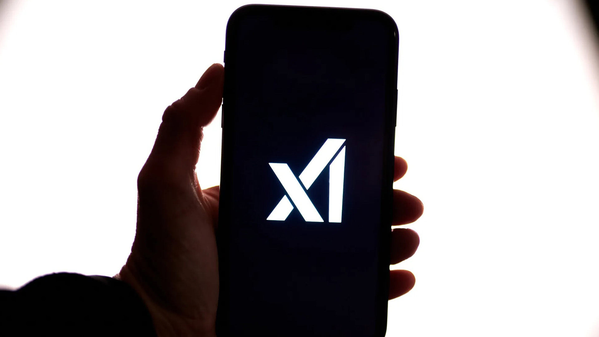 XAI Logo on Mobile Screen | Brimco Hand holding a smartphone with the xai logo illuminated on the screen against a bright white background