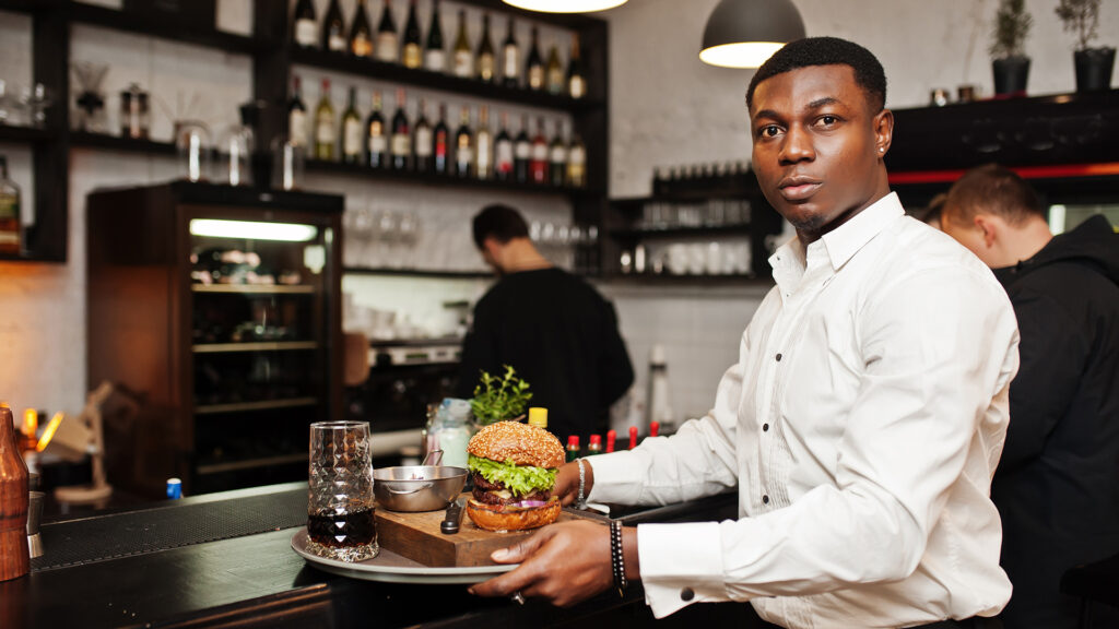 Young restaurant worker serving food representing new restaurant operations and startup challenges