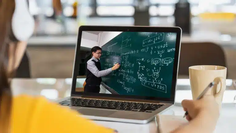 Student attending an online class on a laptop, taking notes while learning complex math equations remotely