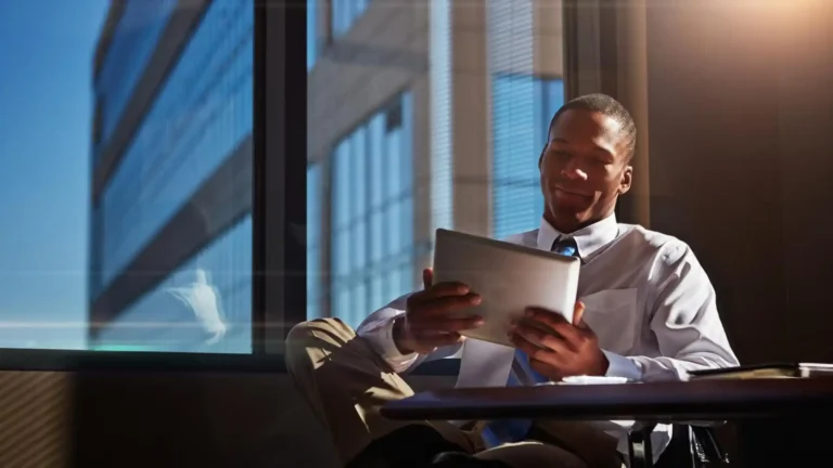 Relaxed young entrepreneur reading on a tablet in a modern office symbolizing startup decision making