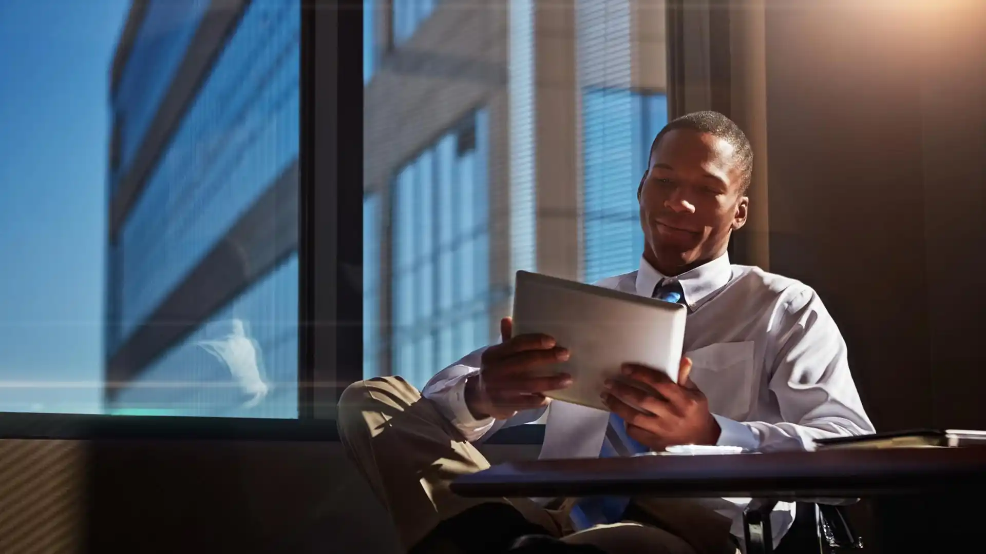 Relaxed young entrepreneur reading on a tablet in a modern office symbolizing startup decision making