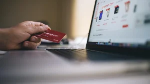 Close up of a person holding a credit card while shopping online using a laptop