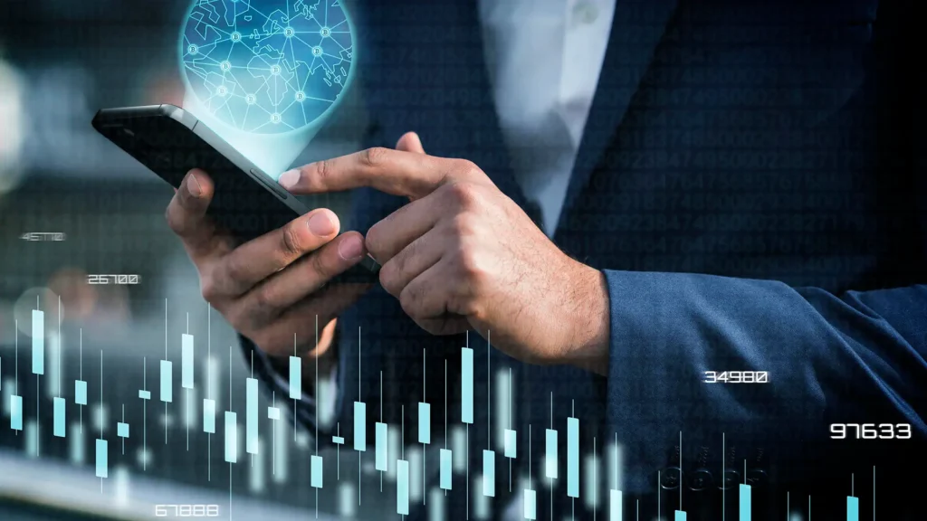 Business professional using a smartphone with financial charts and a global digital interface representing smarter investment tools