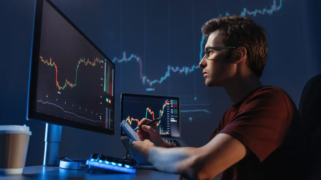 Man analyzing stock market charts using ai trading software on dual monitors