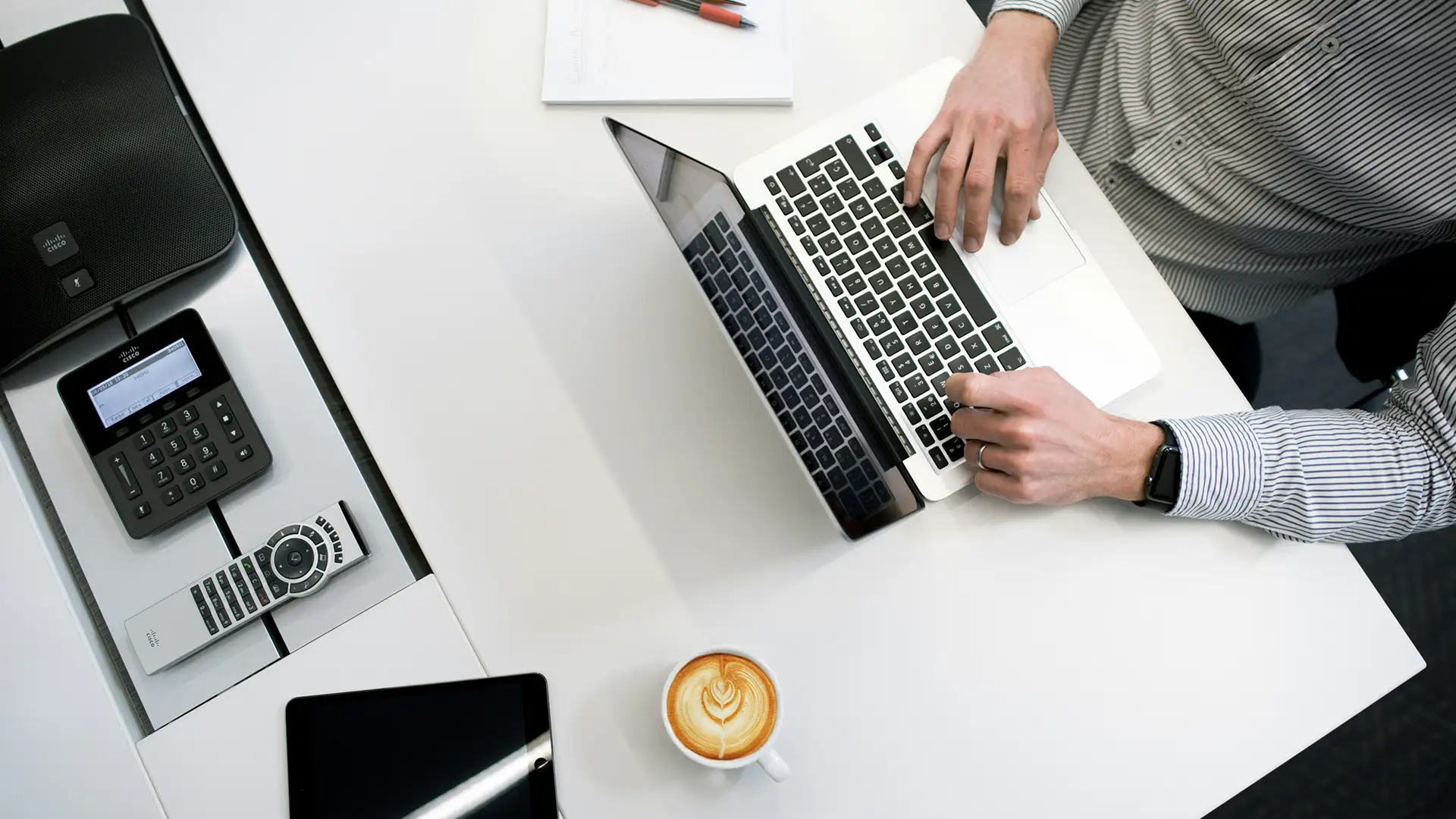 Top down view of a person working on a laptop with a latte
