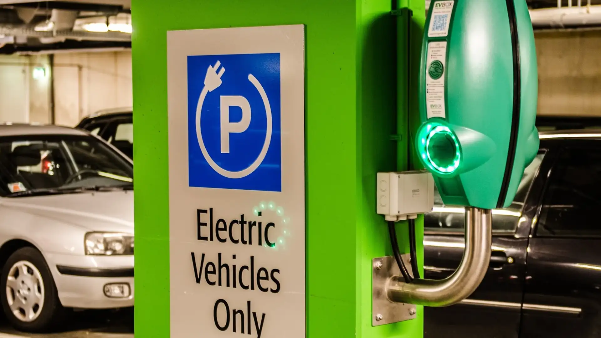 Electric Vehicle Charging Station in Urban Parking Facility | Brimco Electric vehicle charging station in an underground parking garage with a green pillar and electric vehicles only sign