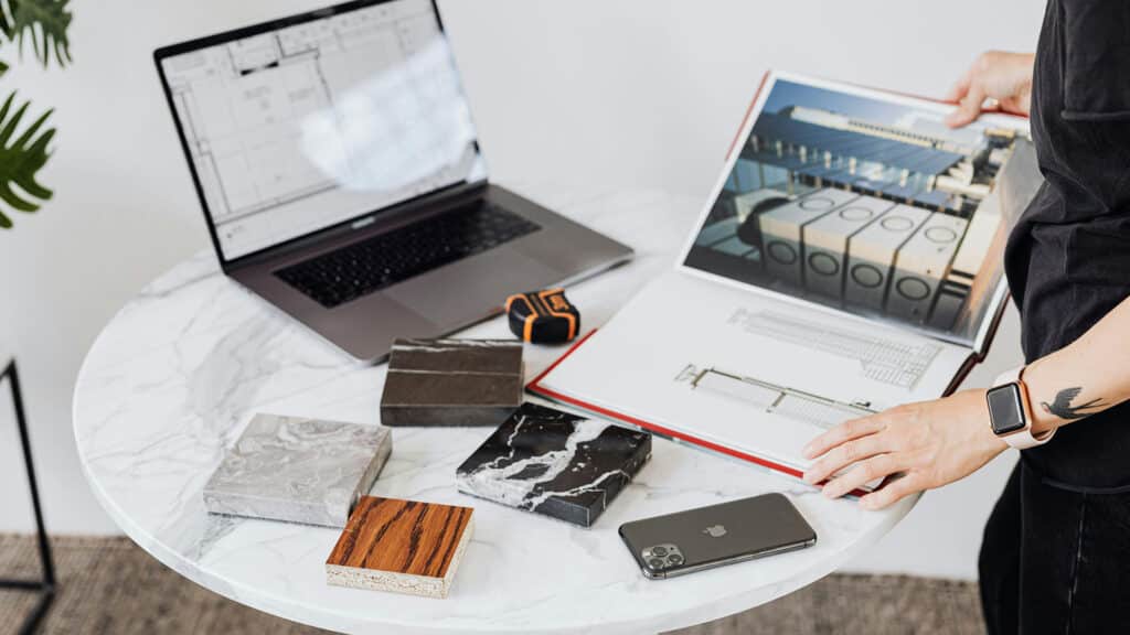 Person reviewing architectural plans with material samples on a marble table