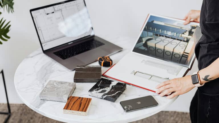 Person reviewing architectural plans with material samples on a marble table