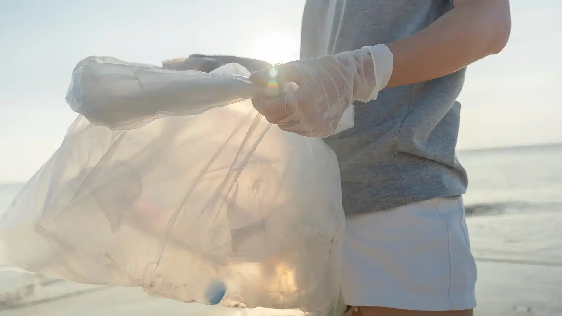 Person holding a plastic bag during a beach cleanup
