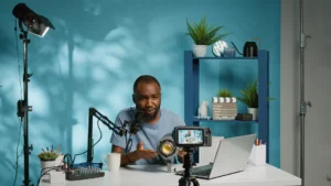 Black content creator recording a video tutorial with camera microphone lighting setup and a laptop in a creative studio