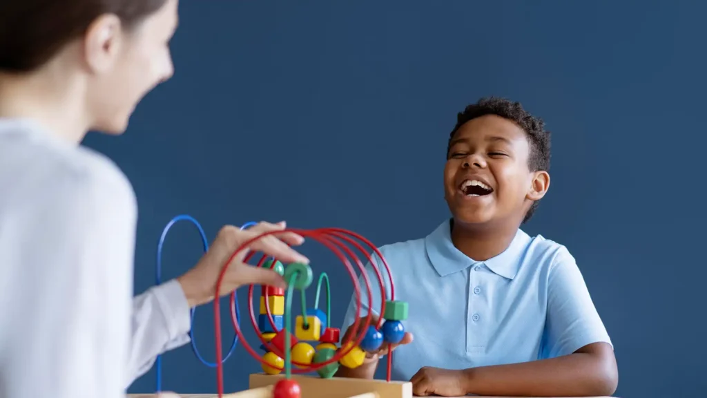 Smiling child engaged in an aba therapy session using educational toys with a therapist in a supportive environment